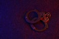 Closed handcuffs on the dark surface at night with police car lights high contrast