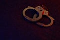 Closed handcuffs on the dark surface at night with police car lights high contrast