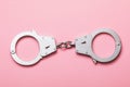 Closed handcuffs on a pink background. Top view on special equipment