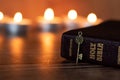 Closed holy bible book and ancient golden key with burning candles on dark background Royalty Free Stock Photo