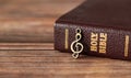 Closed Holy Bible Book with rustic old treble clef note on wooden background Royalty Free Stock Photo