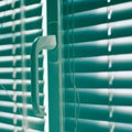 Closed horizontal blinds with rope and handle. Green tone