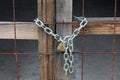 Closed improvised warehouse wooden doors with rusted metal net locked with padlock on strong chain at abandoned military complex