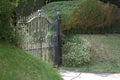 Closed iron driveway gates surrounded by shrubbery