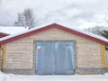 closed iron gate on a gray brick wall of garage outside in white snow Royalty Free Stock Photo