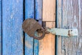 Closed iron lock on wooden battered with weathered cracked blue color door of an old country house Royalty Free Stock Photo