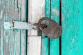 Closed iron lock on wooden battered with weathered cracked paint door of an old country house Royalty Free Stock Photo