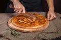 Closed italian pizza Calzone. Man cut the closed italian pizza with a knife. pizza ham, tomato and cheese Royalty Free Stock Photo