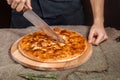 Closed italian pizza Calzone. Man cut the closed italian pizza with a knife. pizza ham, tomato and cheese Royalty Free Stock Photo