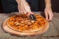 Closed italian pizza Calzone. Man cut the closed italian pizza with a knife. pizza ham, tomato and cheese Royalty Free Stock Photo