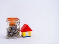 A closed jar of coins with lego house on white background showing savings and home loan concept Royalty Free Stock Photo