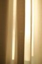 Closed linen curtains hanging on window on a sunny day inside a modern home. Shadow and sunlight shining through cream Royalty Free Stock Photo