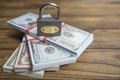 Closed lock and a stack of dollars of banknotes.