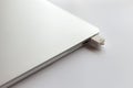 Closed metal laptop on a white table. In the usb connector is inserted 8GB flash drive.