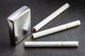 Closed metal lighter and three cigarettes. Royalty Free Stock Photo