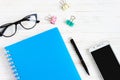 Closed notebook, pen, glasses, mobile phone, a cup of coffee on a white wooden table, flat lay, top view. Office table desk, Royalty Free Stock Photo