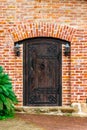 A closed old wooden door with cast-iron awnings and a knock on the doorknob in the form of a twisted ring, vintage lanterns hang Royalty Free Stock Photo