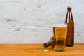 Closed and opened beer bottles with full glass on pub table Royalty Free Stock Photo