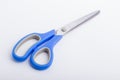 A closed pair of scissors with a blue grip