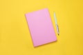 Closed pink notebook and pen on yellow background, flat lay Royalty Free Stock Photo
