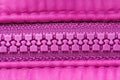 Closed pink plastic zipper closure on clothes, background