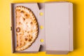 Closed pizza calzone in a packing box on a yellow background Royalty Free Stock Photo