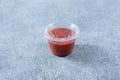 closed plastic condiment cup, red garlic chili sauce, lid