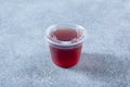 closed plastic condiment cup, red vinaigrette, lid