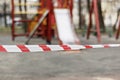 Closed playground during quarantine 2020. White and red warning tape pulled around. Covid-19 Coronavirus Pandemic.Selective focus Royalty Free Stock Photo