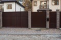 Closed private brown metal gate and part of a brick fence Royalty Free Stock Photo