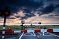 Closed rail crossing at sunrise and windmill