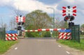 Closed railroad barriers at a rural railway crossing in the polder, Netherlands Royalty Free Stock Photo