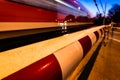 A closed railway barrier in germany with a train in motion and cars waiting