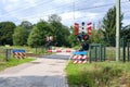 Railway crossing with closed barriers and blinking red lights. Blue warning sign Dutch text,Wait till red light is gone