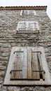 Closed shutters of windows on an old stone wall. Bottom view. Old Rustic facade wall with closed wooden windows. Streets of Kotor Royalty Free Stock Photo