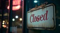 A Closed sign on a door at night with city lights and a neon sign