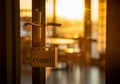 Closed sign hanging on door with sunset lighting in empty cafe interior Royalty Free Stock Photo