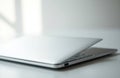 A closed silver laptop resting on a white surface in a bright, minimalistic Royalty Free Stock Photo