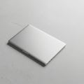 A closed silver laptop rests on a light gray, textured concrete surface. Its sleek design Royalty Free Stock Photo