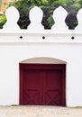 Closed small exit wooden red brown gate door on the massive wall of the THAI GRAND PALACE Royalty Free Stock Photo