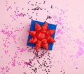 Closed square blue gift box with red bow on a pink background