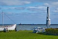 Closed summer cafe umbrella and wooden folding chairs on deserted sunny green lawn against backdrop of boat and seashore Royalty Free Stock Photo