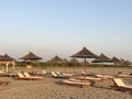 Closed sun umbrellas and empty sun beds on a sandy beach Durres,Albania.