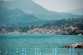 The closed umbrellas on the coast. Ligurian sea. Italy. Mountains and city in the distance.