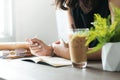 Closed up Asian woman in black dress holding pencil and thinking on blank notebook with eyeglasses, Iced coffee and old books on Royalty Free Stock Photo