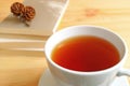 Closed up a cup of hot tea on wooden table with blurred stack of books and dry pine cones on top in background Royalty Free Stock Photo