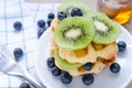 Closed up fresh sliced kiwi and blueberry fruit on top of delicious homemade waffle in white dish Royalty Free Stock Photo