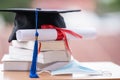 Closed-up photo of a college graduation cap mortarboard with degree diploma certificate and face mask on the table. Graduation in