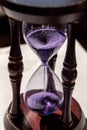 Closed up of sandglass or hourglass with violet, purple sand