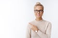 Closed-up shot of beautiful caucasian blond woman in glasses and sweater feeling creative and productive pointing at